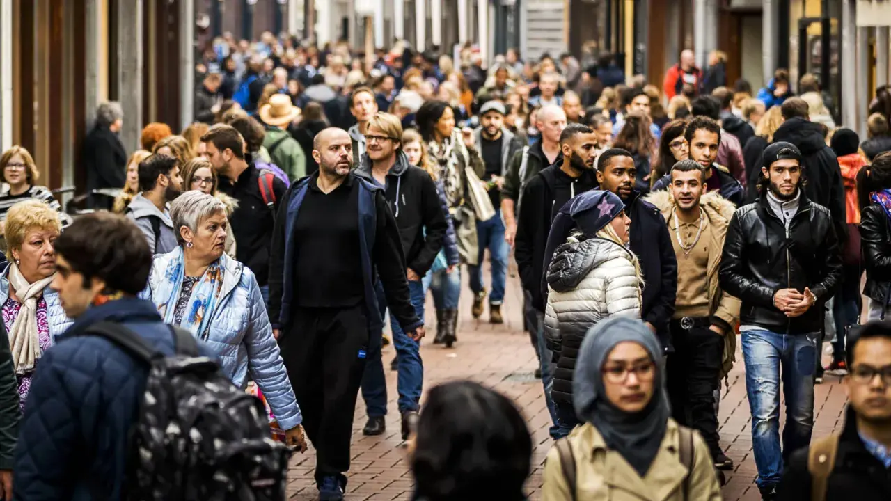 A diverse crowd of people walks down a busy street in the Netherlands.