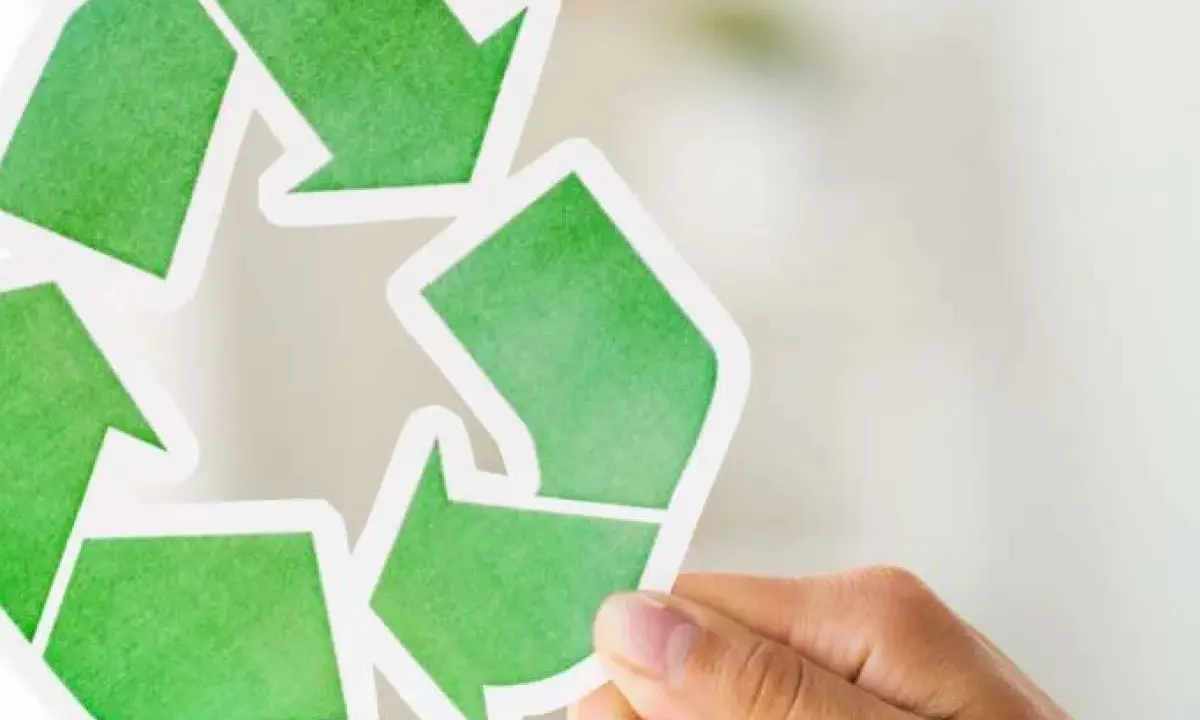 Hand holds a green recycling symbol, representing duurzaam ondernemen.