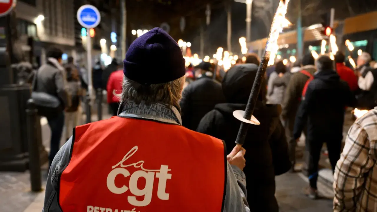 Demonstranten met fakkels protesteren tegen de pensioenleeftijd in Frankrijk. Op de rode vesten staat "CGT".