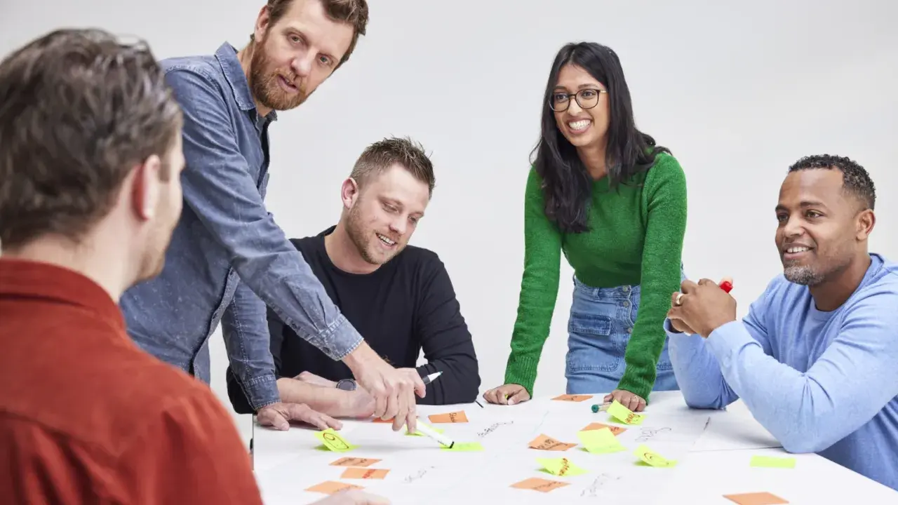 Een team, waaronder Karin Geuijen, brainstormt met post-its op een tafel.