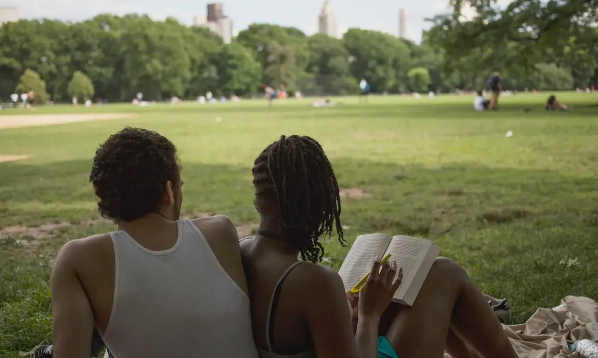 Een stel geniet van een zonnige dag in het park. Ze zitten op een kleed, de vrouw leest een boek, de man kijkt naar het landschap. Ze hebben de derde plaats in de wedstrijd 'meest ontspannen duo'.