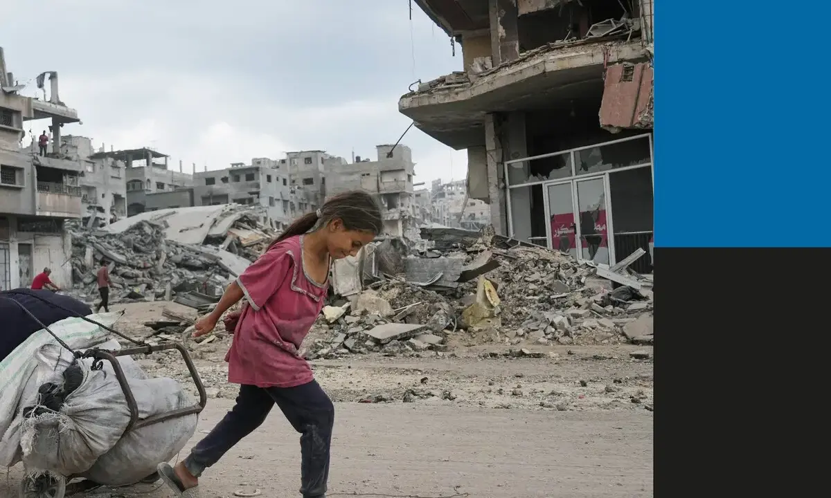 Een meisje sleept een kar met spullen door de verwoesting van de oorlog in Gaza. Gebouwen liggen in puin, een triest beeld van de impact op burgers.