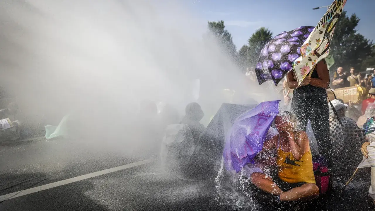 Protest met waterkanonnen, mensen met paraplu's tonen burgerlijke ongehoorzaamheid.