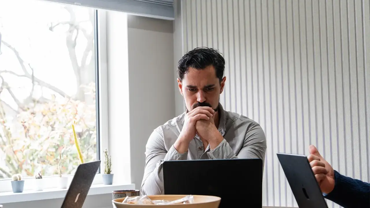 Man denkt diep na over beleid en maatschappij, omringd door laptops en plantjes.