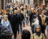 A diverse crowd of people walks down a busy street in the Netherlands.