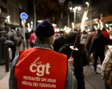 Demonstranten met fakkels protesteren tegen de pensioenleeftijd in Frankrijk. Op de rode vesten staat "CGT".