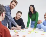 Een team, waaronder Karin Geuijen, brainstormt met post-its op een tafel.