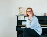 Annelien de Dijk, met een blik vol vrijheid, zit bij een piano, omringd door muziek en een telraam.
