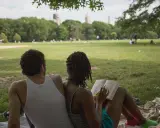Een stel geniet van een zonnige dag in het park. Ze zitten op een kleed, de vrouw leest een boek, de man kijkt naar het landschap. Ze hebben de derde plaats in de wedstrijd 'meest ontspannen duo'.