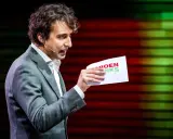 Man met krullend haar, in grijs pak, houdt een papier met "GROENLINKS" vast. Discussie over de Moslimbroederschap?