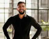 Man in zwart overhemd, handen in de zij, straalt zelfvertrouwen uit met een krachtige power pose.