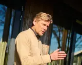 Man met blonde haren, gekleed in een beige jasje, legt met zijn hand uit hoe wordt ik assertiever.