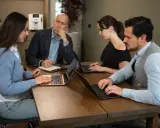 Teamoverleg: de betekenis van delegeren wordt duidelijk als de manager taken verdeelt en de teamleden geconcentreerd werken aan hun laptops.