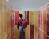 Meisje met rugzak bij schoolkluisjes. Ze overweegt of ze van 3 havo naar 4 mavo kan.