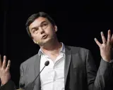 Economist Thomas Piketty spreekt met gebaren, zijn handen omhoog, terwijl hij een lezing geeft.