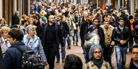 A diverse crowd of people walks down a busy street in the Netherlands.