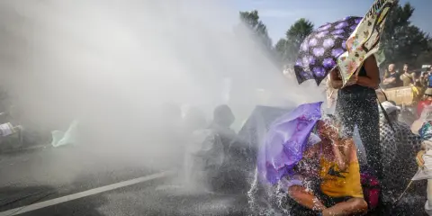Protest met waterkanonnen, mensen met paraplu's tonen burgerlijke ongehoorzaamheid.