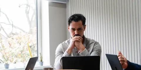 Man denkt diep na over beleid en maatschappij, omringd door laptops en plantjes.