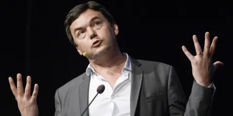 Economist Thomas Piketty spreekt met gebaren, zijn handen omhoog, terwijl hij een lezing geeft.