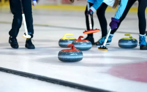 Curling ouders met hun stenen op het ijs. De spelers buigen zich voorover, klaar om te gooien.