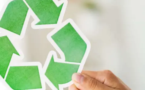 Hand holds a green recycling symbol, representing duurzaam ondernemen.