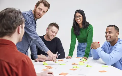 Een team, waaronder Karin Geuijen, brainstormt met post-its op een tafel.