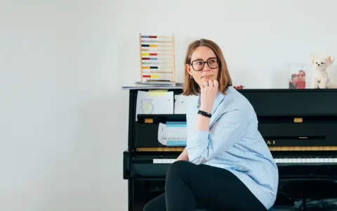 Annelien de Dijk, met een blik vol vrijheid, zit bij een piano, omringd door muziek en een telraam.