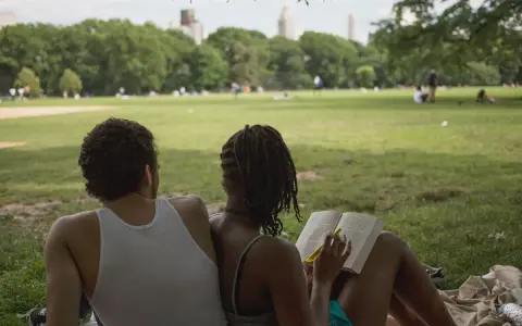 Een stel geniet van een zonnige dag in het park. Ze zitten op een kleed, de vrouw leest een boek, de man kijkt naar het landschap. Ze hebben de derde plaats in de wedstrijd 'meest ontspannen duo'.