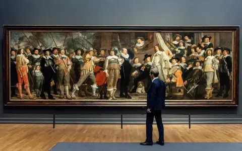 Man kijkt naar De Nachtwacht, een schilderij dat de Nederlandse nationale identiteit weerspiegelt met zijn dynamische groepsportret van schutters.