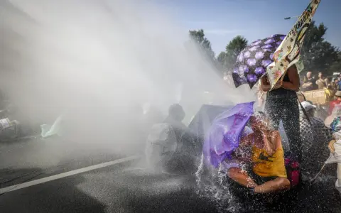 Protest met waterkanonnen, mensen met paraplu's tonen burgerlijke ongehoorzaamheid.