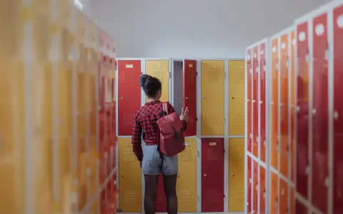 Meisje met rugzak bij schoolkluisjes. Ze overweegt of ze van 3 havo naar 4 mavo kan.