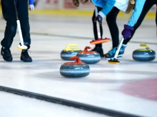 Curling ouders met hun stenen op het ijs. De spelers buigen zich voorover, klaar om te gooien.