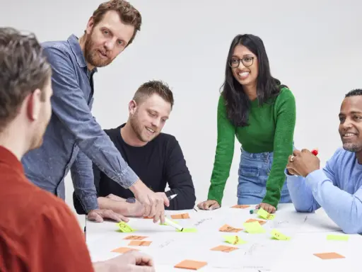 Een team, waaronder Karin Geuijen, brainstormt met post-its op een tafel.