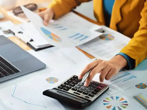 Persoon berekent cijfers op een calculator, omringd door grafieken en documenten. Dit kan te maken hebben met de commissie sociaal minimum.
