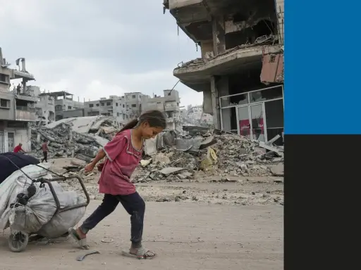 Een meisje sleept een kar met spullen door de verwoesting van de oorlog in Gaza. Gebouwen liggen in puin, een triest beeld van de impact op burgers.