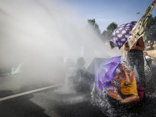 Protest met waterkanonnen, mensen met paraplu's tonen burgerlijke ongehoorzaamheid.