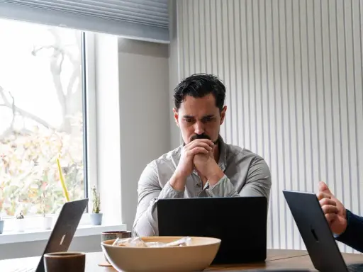 Man denkt diep na over beleid en maatschappij, omringd door laptops en plantjes.
