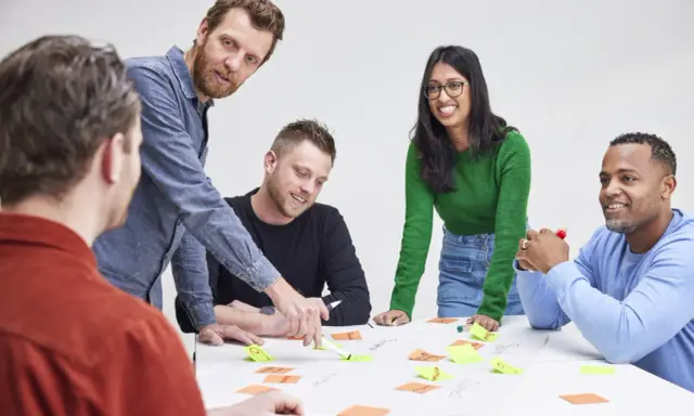 Een team, waaronder Karin Geuijen, brainstormt met post-its op een tafel.