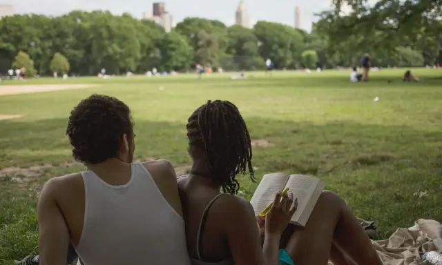 Een stel geniet van een zonnige dag in het park. Ze zitten op een kleed, de vrouw leest een boek, de man kijkt naar het landschap. Ze hebben de derde plaats in de wedstrijd 'meest ontspannen duo'.