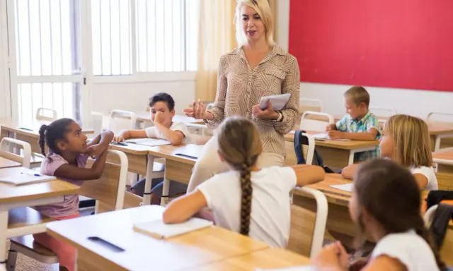 Een lerares geeft les aan een klas, waarbij ze de principes van psychologie in het onderwijs toepast om leerlingen te betrekken.