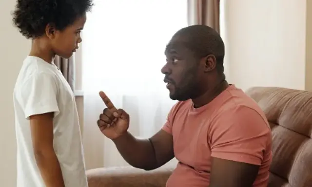 A man in a pink shirt points his finger at a child in a white shirt.