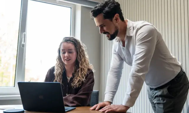 Man en vrouw kijken samen naar een laptop, ter voorbereiding op een gesprek met HR.