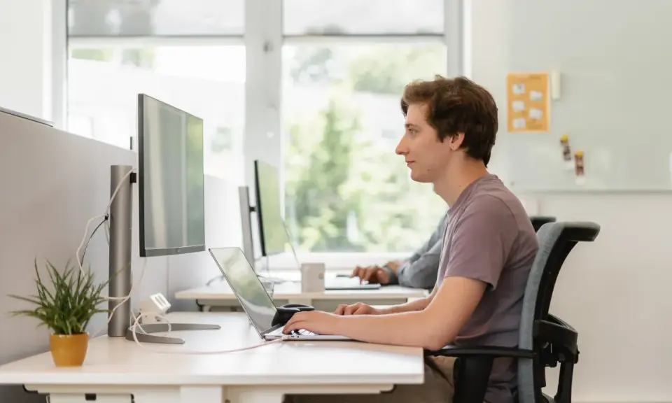 Jonge man werkt geconcentreerd aan laptop. Dit is een voorbeeld van self assessment betekenis: reflecteren op eigen werk.
