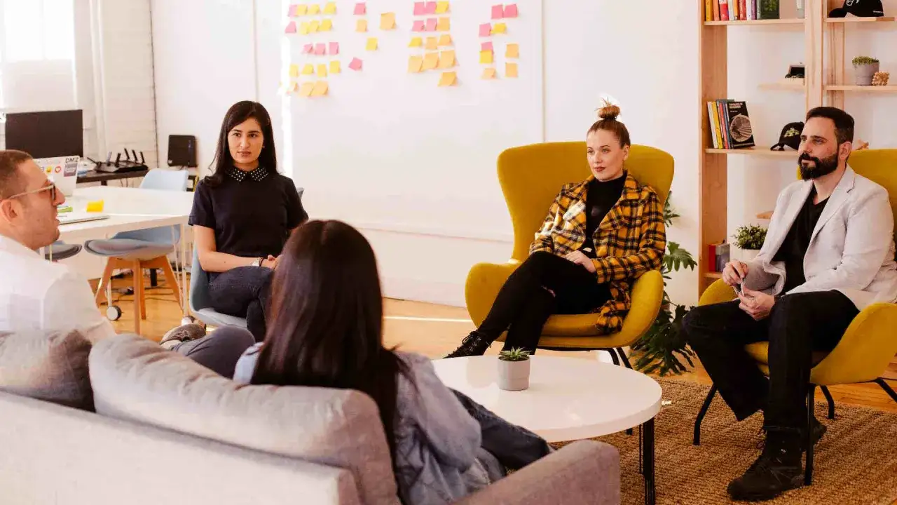 Een team bespreekt ideeën in een open kantoorruimte, wat duidt op psychologische veiligheid en open communicatie.