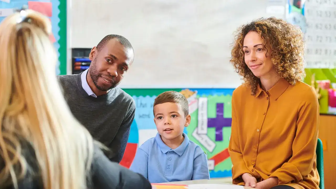 Een leraar en een moeder praten met een jongen in de klas. Goede communicatie met ouders is essentieel voor de ontwikkeling van het kind.