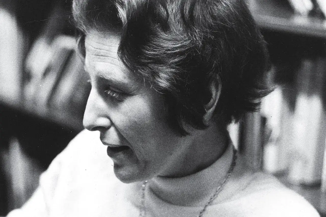 Judith Shklar, met haar kenmerkende kapsel en peinzende blik, in een moment van diepe gedachten te midden van boeken.
