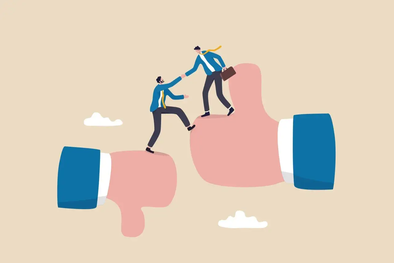 Twee mannen in pakken helpen elkaar omhoog, van een duim-omlaag naar een duim-omhoog. Een metafoor voor een gesprek met HR voorbereiden.