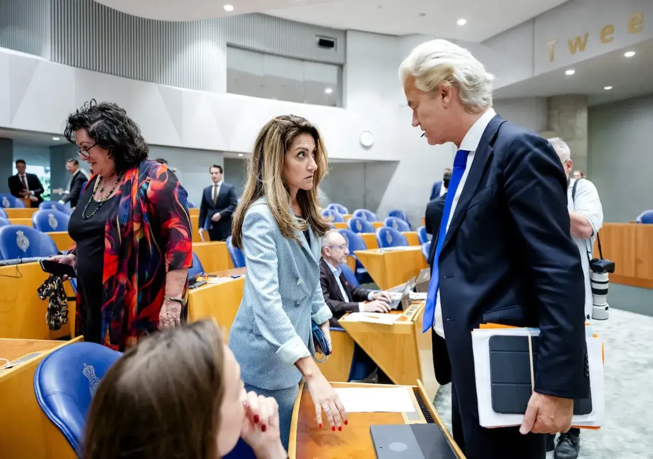 Geert Wilders in gesprek met een vrouw in de Tweede Kamer. De sfeer is gespannen, mogelijk een vooruitblik op een toekomstig wilders kabinet.