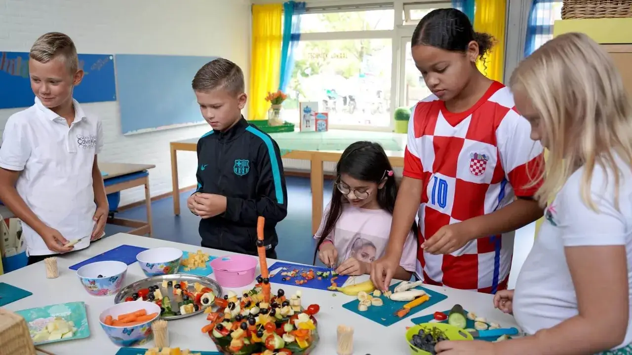Kinderen maken fruitspiesjes tijdens de gouden weken onderwijs. Ze snijden fruit en groenten, een creatieve en gezonde activiteit.