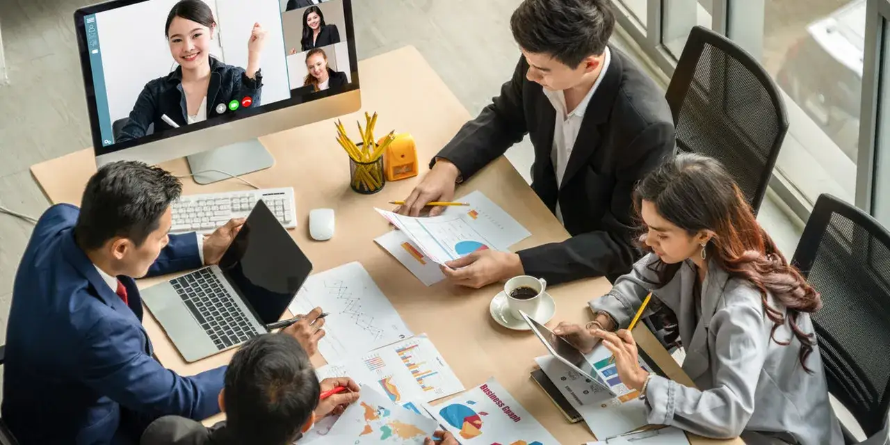 Teamleden werken samen aan een project, met een videogesprek op het scherm. Ze bespreken grafieken en rapporten, wat efficiënte samenwerking met collega's laat zien.